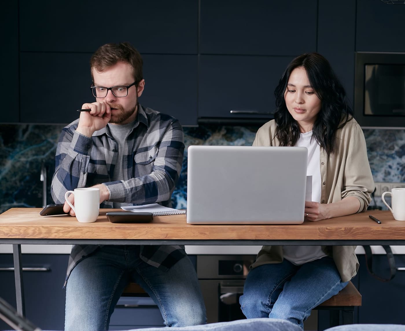 Two people sitting together at a kitchen table looking at a laptop
